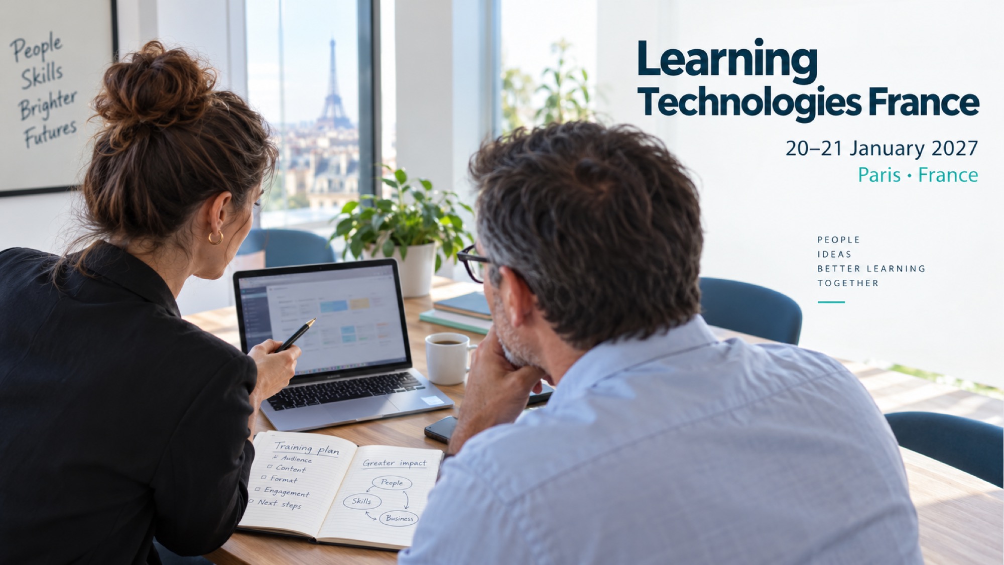 Two business professionals discuss a training plan and laptop at a meeting table.