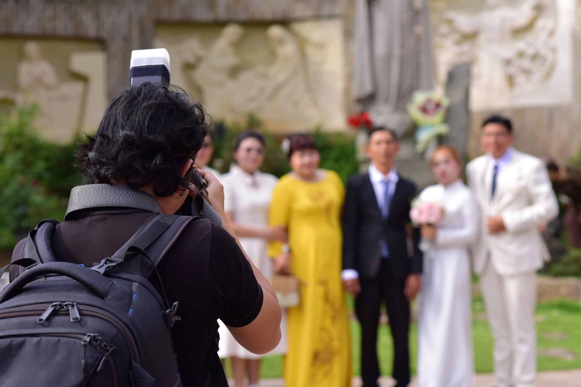 Photographer using a still camera to photograph a wedding couple and their group outdoors