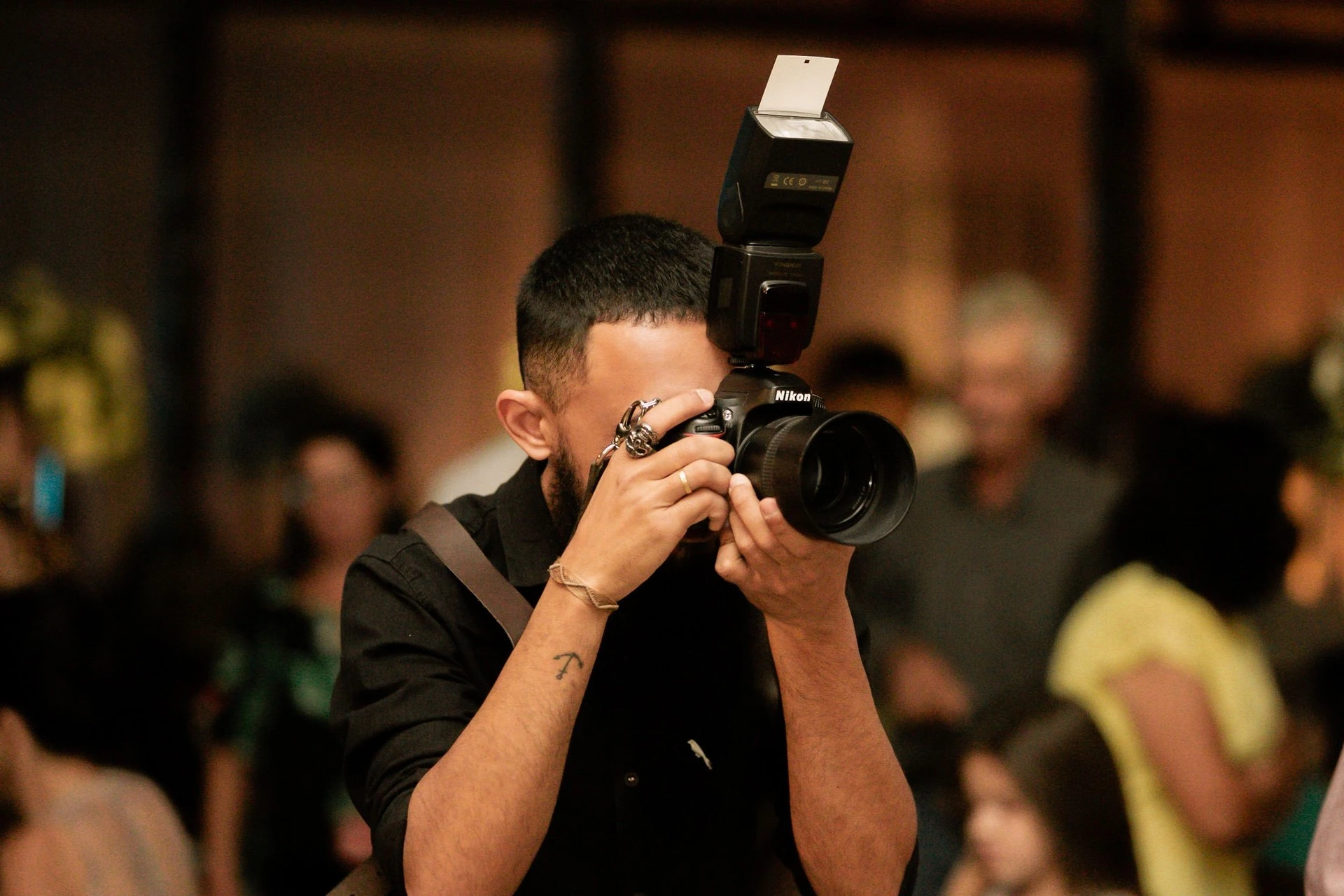 Photographer using a DSLR camera and flash among guests at an indoor event