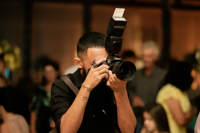 Photographer using a DSLR camera and flash among guests at an indoor event
