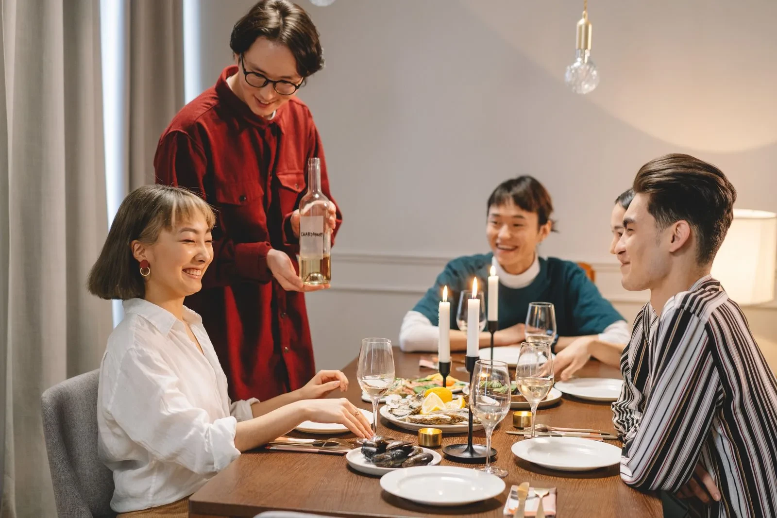 Des amis sourient et discutent autour d’une table à manger à l’intérieur.
