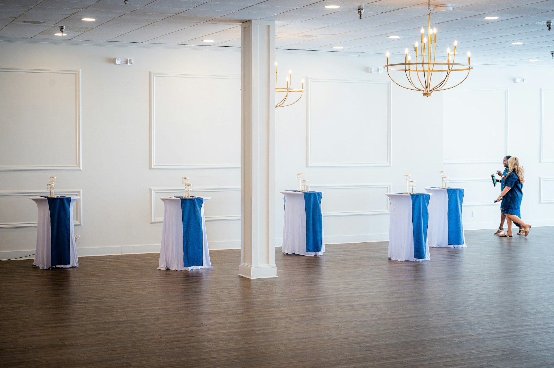 Bright reception room with blue and white high tables and gold chandeliers